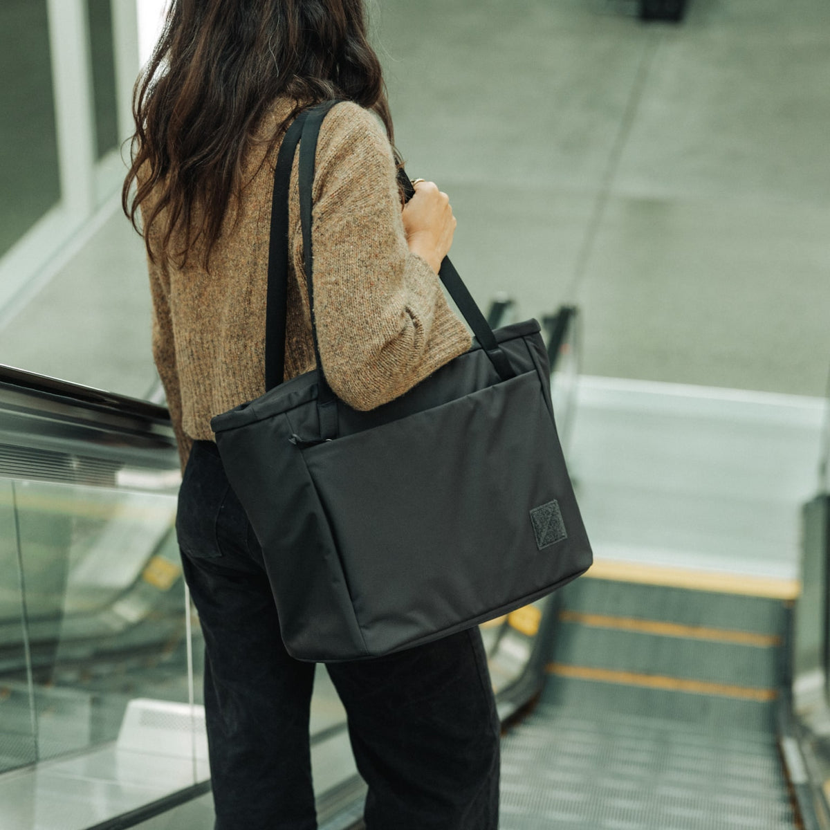 CIVIC Daily Tote 24L in Solution Dyed Black - CDT24 - shoulder carry going down escalator CIVIC Daily Tote 24L in Solution Dyed Black - CDT24 - shoulder carry going down escalator [13024a-SBK