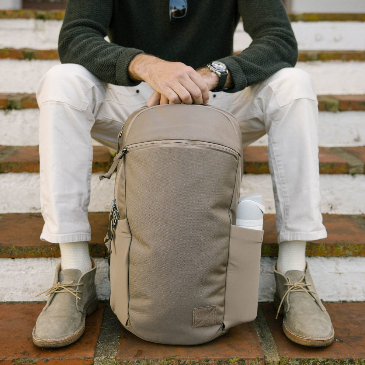 Person sitting on steps with a CIVIC Half Zip 22L in Fossil Brown backpack Person sitting on steps with a CIVIC Half Zip 22L in Fossil Brown backpack [13003d-FBN