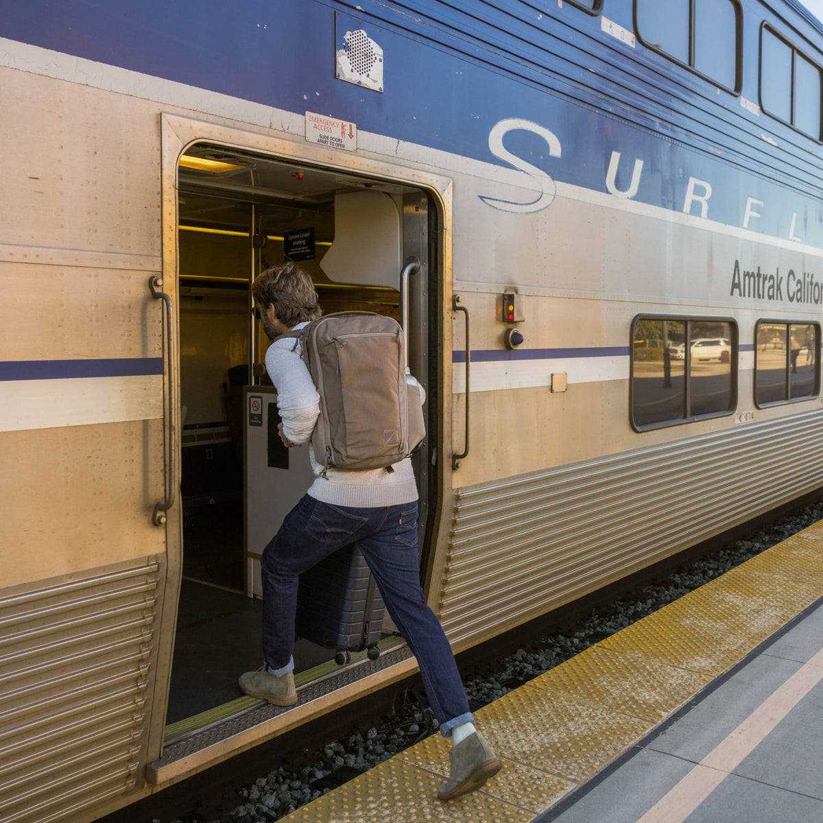 Person boarding an Amtrak train on a platform wearing a CIVIC Travel Bag 26L in Fossil Brown Person boarding an Amtrak train on a platform wearing a CIVIC Travel Bag 26L in Fossil Brown [13012c-FBN