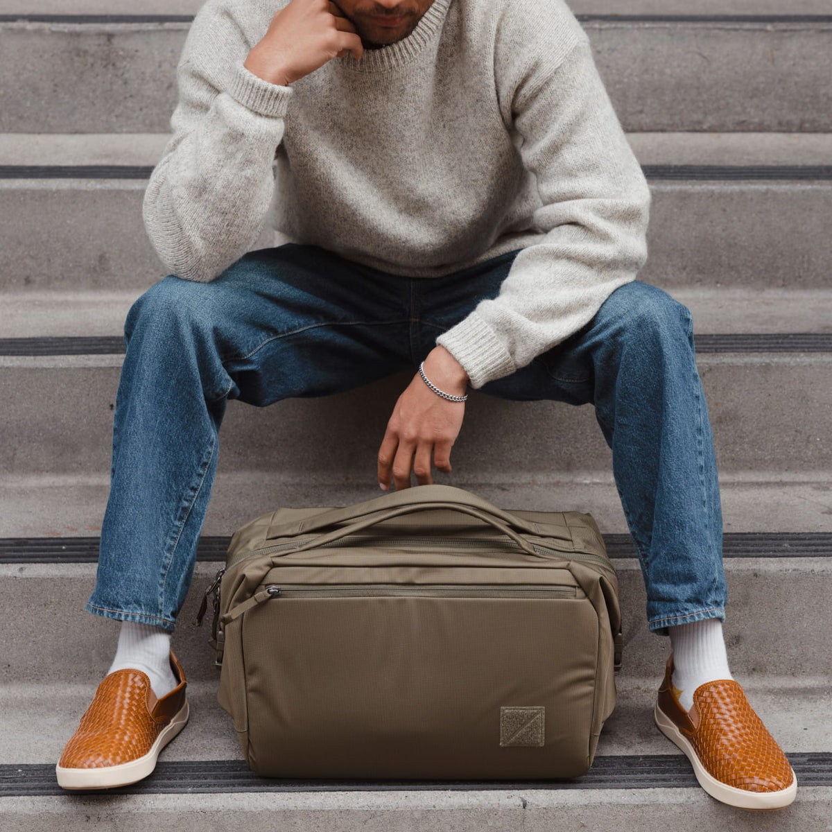 Person sitting on steps with a Transit Duffel 25L in OD Green in front of them Person sitting on steps with a Transit Duffel 25L in OD Green in front of them [13023d-ODG