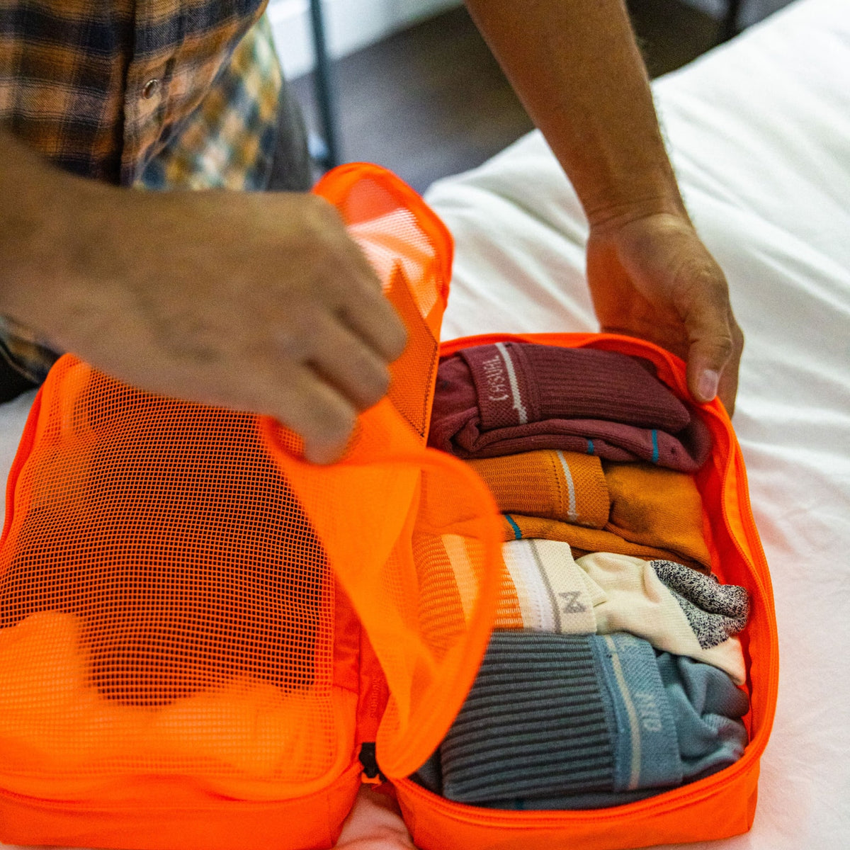 Transit Packing Cube 8L in Hot Orange open on bed Transit Packing Cube 8L in Hot Orange open on bed [13015a-HTO