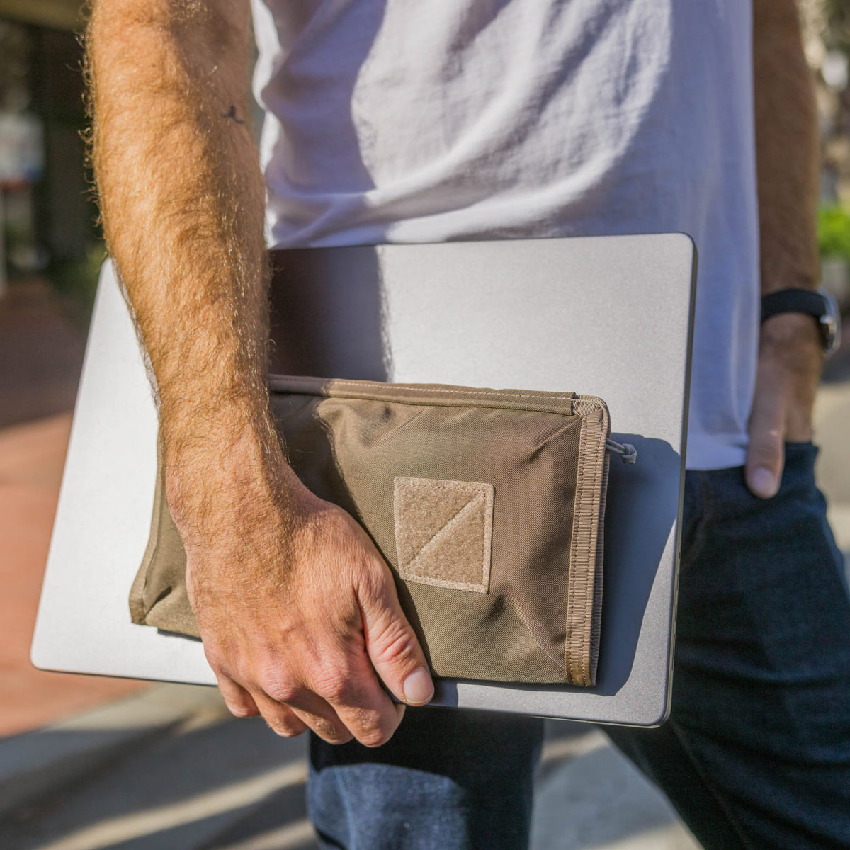 Person holding a laptop with a CIVIC Access Pouch 1L in Fossil Brown attached on a blurred outdoor background [13009a-FBN]