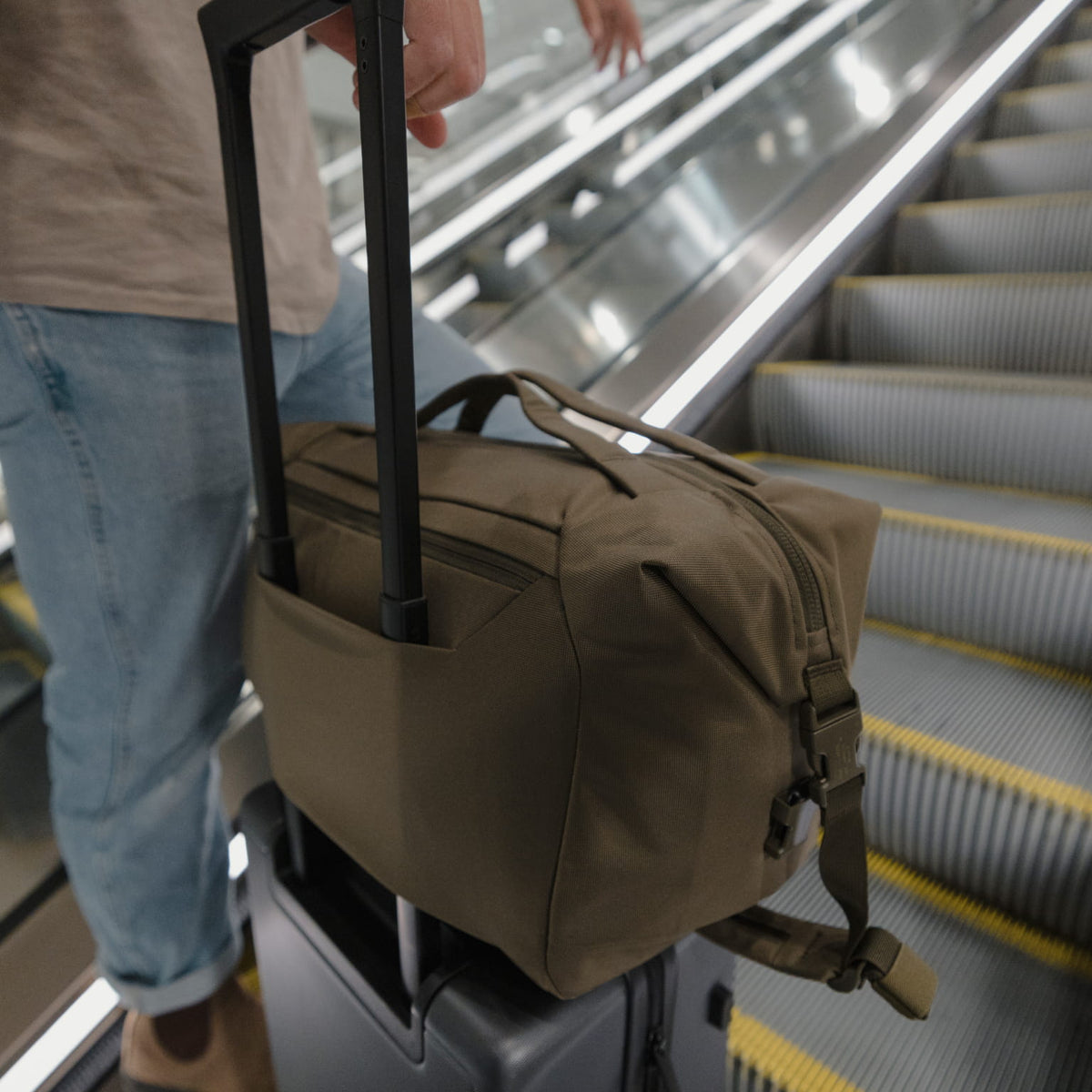 ransit Duffel 25L in OD Green on roller luggage in airport escalator [13023d-ODG]