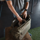 Person organizing items in a Transit Duffel 25L in OD Green on a bench in an indoor gym setting Person organizing items in a Transit Duffel 25L in OD Green on a bench in an indoor gym setting [13023d-ODG