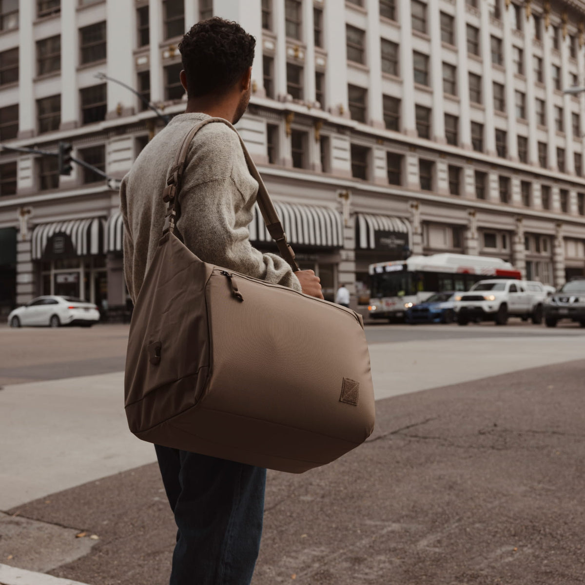 Transit Duffel 35L in Fossil Brown carried in a city [13014d-FBN]