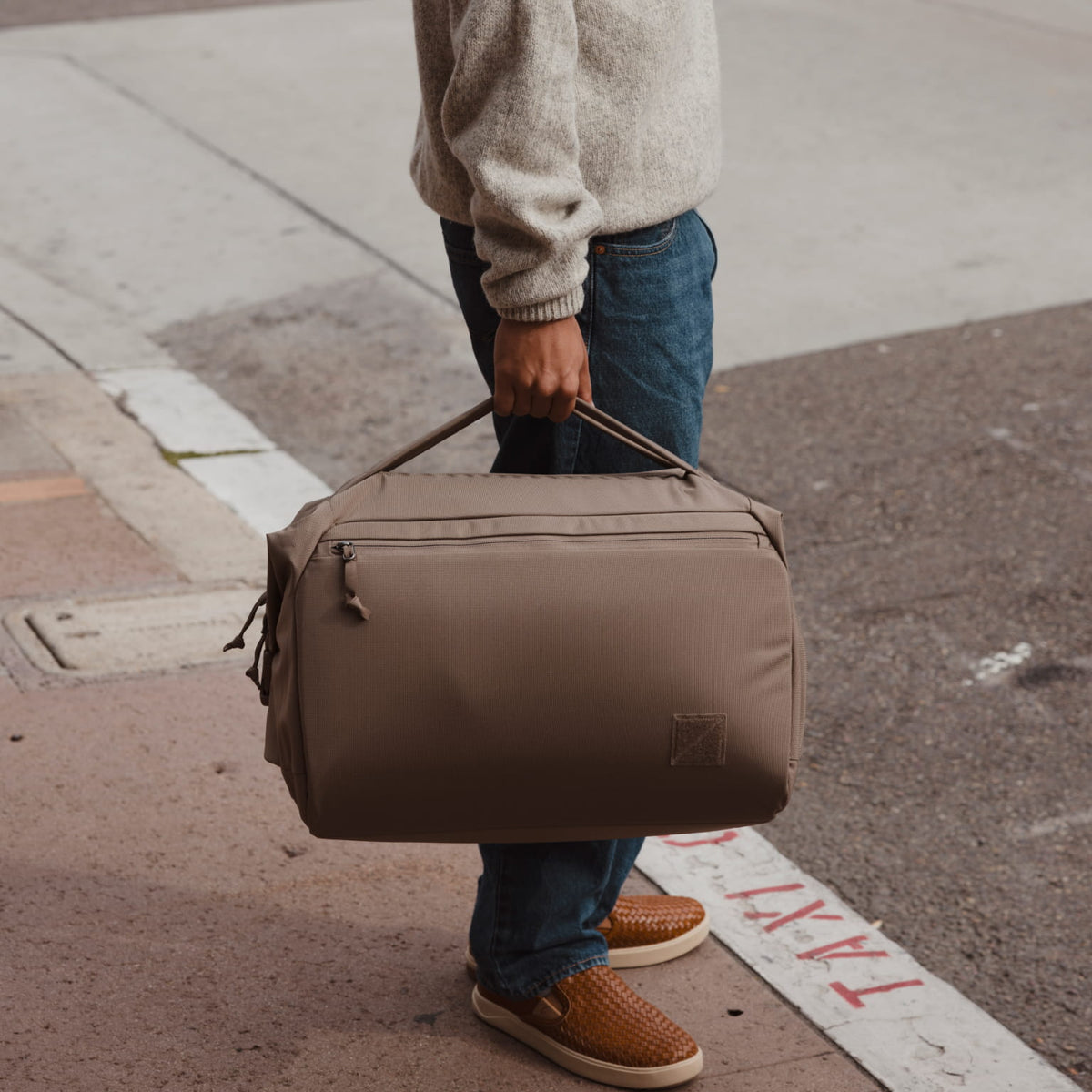 Transit Duffel 35L in Fossil Brown carried in a city by hand [13014d-FBN]