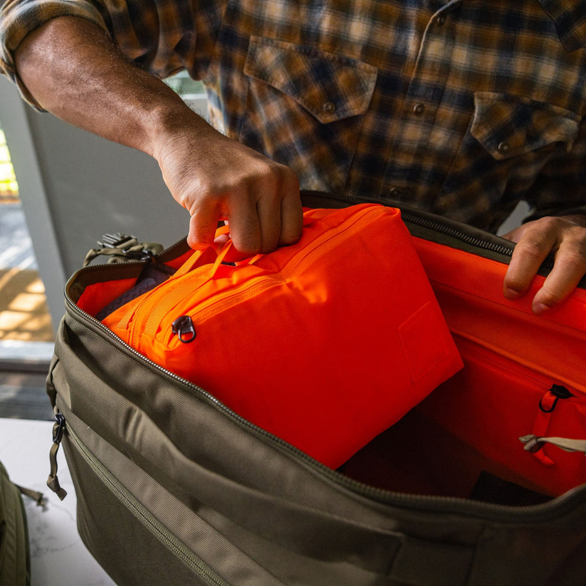 Transit Packing Cube 8L in Hot Orange coming out of Transit Duffel 35L [13015a-HTO]
